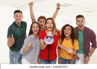 Group of happy young people with megaphone indoors