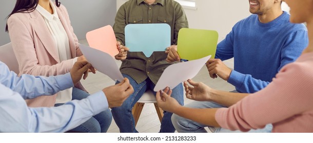 Group of happy young people sitting in circle and holding message bubbles. Team of men and women talking and sharing opinions. Cropped shot. Banner background. Communication and discussion concepts