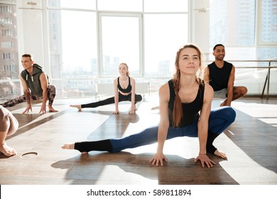 Group Of Happy Young People Working Out In Yoga Studio