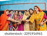Group of happy young traditional indian women wearing colorful sari join hands with each other like a team. Rural india. women empowerment. World women