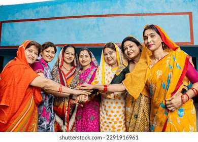 Group of happy young traditional indian women wearing colorful sari join hands with each other like a team. Rural india. women empowerment. World women's day, Top view