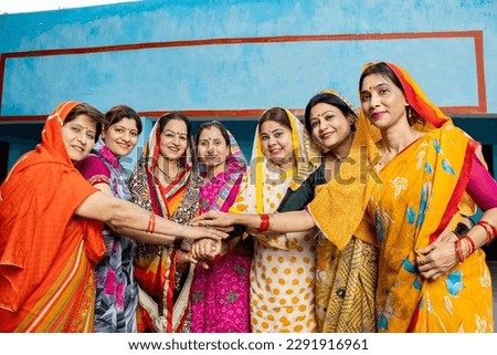 Group of happy young traditional indian women wearing colorful sari join hands with each other like a team. Rural india. women empowerment. World women's day, Top view