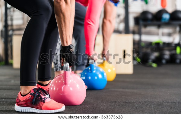 Group having functional fitness training with\
kettlebell in sport gym