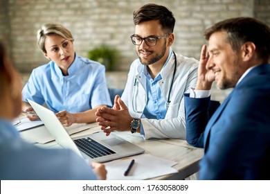 Group of healthcare workers and businessman using laptop while having a meeting in the office. Focus is on young doctor. 