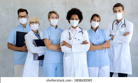 Group of healthcare workers wearing protective face masks while standing with arms crossed and looking at camera. 
