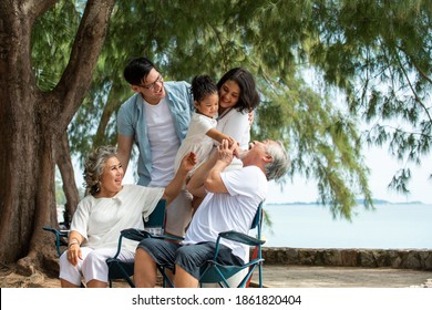 Group Of Healthy Multi Generation Asian Family Enjoy Picnic Travel Together On The Beach. Parents With Cute Child Girl And Healthy Senior Grandparents Relax And Having Fun On Summer Holiday Vacation
