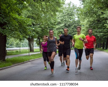 Gruppe gesunder Menschen, die im Stadtpark joggen, Läufer-Team am Morgen-Training