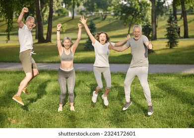 Group of healthy runners team jumping in the air at city park during morning training. - Powered by Shutterstock