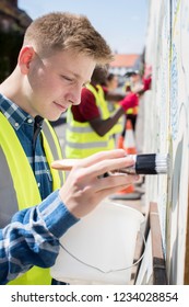 Group Of Helpful Teenagers Creating And Maintaining Community Art Project