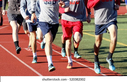 A Group Of High School Boys Running In A Group On A Red Track