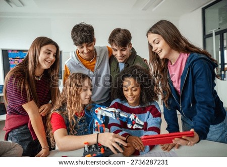 Group of high school students building robotic arm in STEM classroom.
