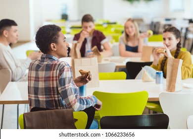 Group Of High School Students Chatting While Taking Lunch At School Cafeteria