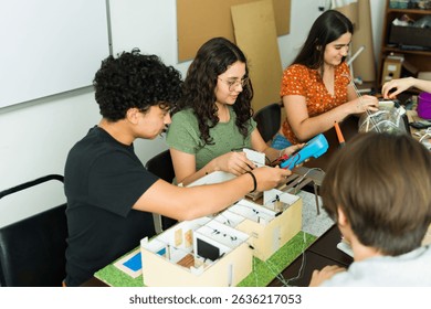 Group of high school students collaborating on an electronics project, using a multimeter and other tools, during a stem class