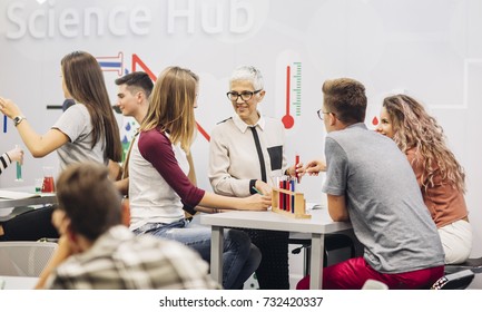 Group of high school students doing experiments on chemistry class with their teacher.