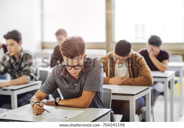 Group of\
high school students doing exam at\
classroom.