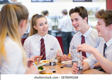 Un groupe d'élèves du secondaire déjeunant à la cafétéria de l'école. : photo de stock
