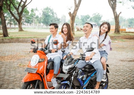 Group of high school students joking while riding a motorcycle without helmet on the road