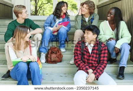 A group of high school students are sitting on the steps of the school, laughing and joking. They are all smiling and happy, and they seem to be having a lot of fun.Friendship and joy of youth concept