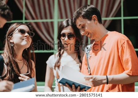 A group of high school students studies together outdoors while sharing notebooks. Young friends consult notes and discuss schoolwork in a casual, sunny setting.