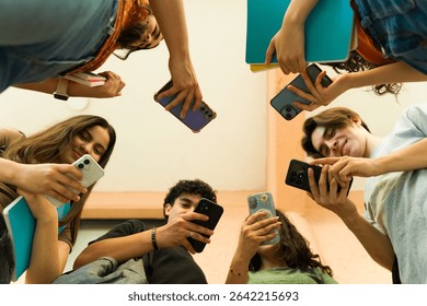 Group of high school students using their smartphones and holding notebooks, standing in a circle