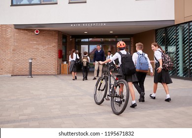Group Of High School Students Wearing Uniform Arriving At School Walking Or Riding Bikes Being Greeted By Teacher - Shutterstock ID 1195671832