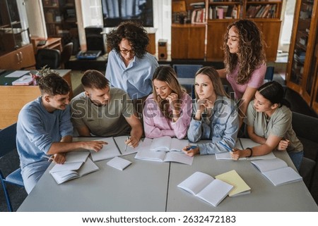 Group of high school students work on project and study with teacher in library