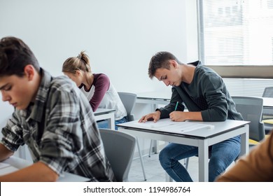 Group of high school students writing at classroom.