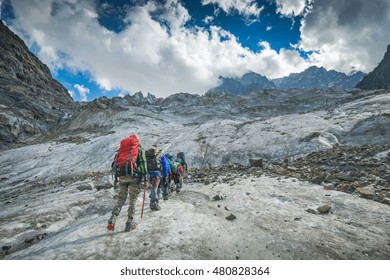 Group Of Hikers With Backpacks Climb The Glacier To The Peak Of Mountain. Caucasian Mountains, Georgia, Svaneti Region.