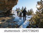 group of hikers crosses a rocky passage on snowshoes