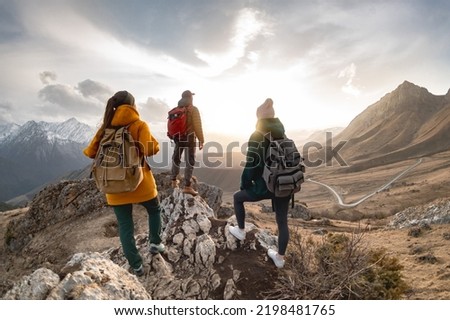 Group of hikers or tourists with backpacks walks in mountains at sunset