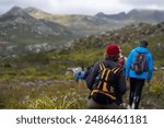 A group of hikers trekking with backpacks and other necessary equipment along a rugged mountain trail.