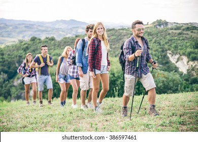 Group of hikers walking in the nature - Friends taking an excursion on a mountain, walking in a row - Shutterstock ID 386597461
