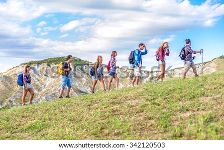 Group of hikers walking in the nature  - Friends taking an excursion on a mountain, walking in a row