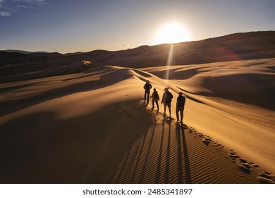 Group of hikers are walking at sunset desert dune. Long beautiful shadows on sand dunes - Powered by Shutterstock