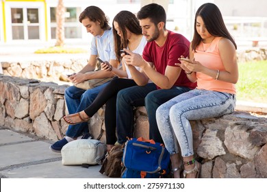 Group of Hispanic college students ignoring each other and using their cell phones