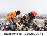 Group of homeless street children collecting garbage in a steaming landfill in an African metropolis; concept of poverty and neglect of children