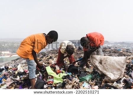 Group of homeless street children collecting garbage in a steaming landfill in an African metropolis; concept of poverty and neglect of children