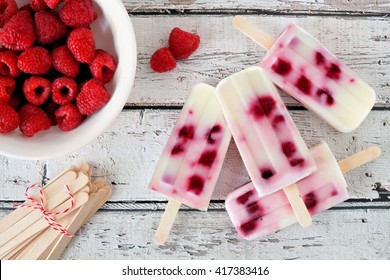 Group of homemade raspberry vanilla popsicles on a rustic white wood background