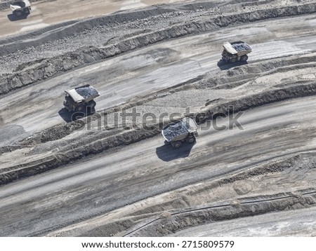 Group of huge mining trucks transporting ore from the bottom of the mine to the open pit.