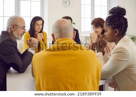 Group of humble pious religious diverse multiracial multiethnic people sitting around table, praying together, feeling united, saying prayer of gratitude, thanking God for grace. Discipleship