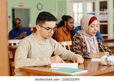 Group of immigrant students in international class sitting at desk reading and making notes during lesson - Shutterstock ID 2160232395