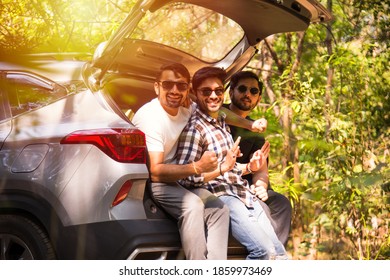 Group Of Indian Asian Young And Attractive Friends Sitting In The Open Trunk Of A Car, A Summer Road Trip