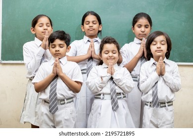 Group of indian elementary school kids join hands and offer prayer in class room. - Powered by Shutterstock