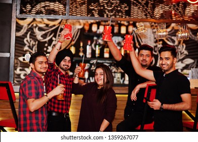  Group Of Indian Friends Having Fun And Rest At Night Club, Drinking Cocktails, Clinking And Cheers Near Bar Counter.