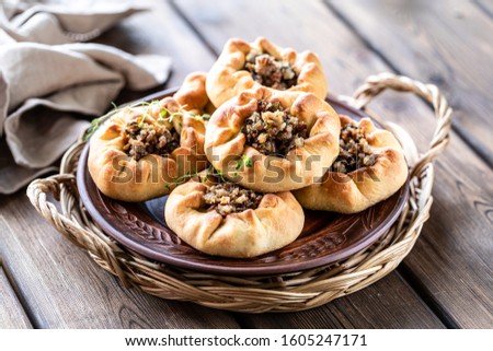 Group of individual pies with meat and potato - vak balish. Tatar traditional pies. Wooden background