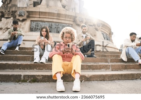 Group of individualistic people using phone outdoors with serious face. Friends focused on their mobiles ignoring each others outdoors. Technology addicts concept. High quality photo