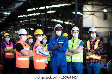 Group Of Industrial Worker Team Consist Of Technicians, Engineer, Factory Manager Wearing Helmet And Surgical Mask To Protect Coronavirus, Covid-19 Inflection And Safety Working In Manufacturing Plant