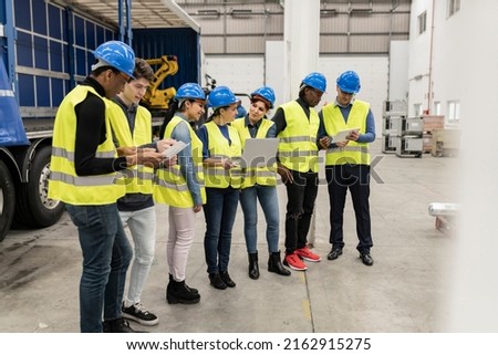 group of ingenious workers in robotics, apprentice engineer programming robots in car factory