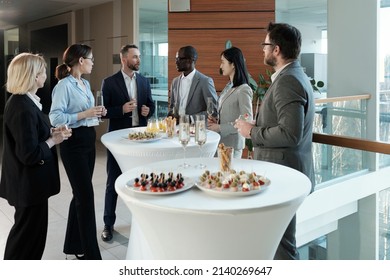 Group Of Intercultural Business People In Formalwear Looking At Man With Flute Of Champagne Pronouncing Toast For Successful Project