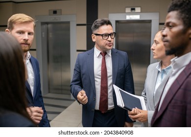 Group Of Intercultural Business People Interacting In Corridor Of Large Contemporary Office Center